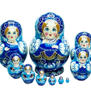 Puede incluir: Un conjunto de 10 mu&ntilde;ecas rusas de anidaci&oacute;n, o mu&ntilde;ecas matrioska, azules y blancas, con intrincados dise&ntilde;os florales y detalles dorados. La mu&ntilde;eca m&aacute;s grande mide aproximadamente 25 cm de alto y la m&aacute;s peque&ntilde;a aproximadamente 2,5 cm.