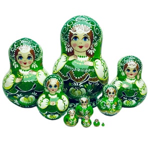 May include: A set of 8 green and white Russian nesting dolls, also known as matryoshka dolls. The dolls are painted with floral designs and feature the traditional Russian folk art style.