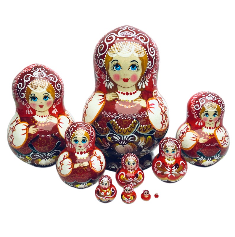 Puede incluir: Un conjunto de ocho mu&ntilde;ecas rusas de anidaci&oacute;n, tambi&eacute;n conocidas como mu&ntilde;ecas matryoshka, de color rojo y blanco. Las mu&ntilde;ecas est&aacute;n pintadas con dise&ntilde;os florales tradicionales y tienen caras sonrientes. La mu&ntilde;eca m&aacute;s grande mide aproximadamente 25 cm de alto y la m&aacute;s peque&ntilde;a aproximadamente 2,5 cm.
