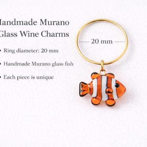 K&ouml;nnte beinhalten: Handgefertigter Murano-Glas-Wein-Charm mit einem Clownfisch-Design. Der goldfarbene Ring hat einen Durchmesser von 20 mm. Der Fisch ist orange, wei&szlig; und schwarz. Jedes St&uuml;ck ist einzigartig. Der Text lautet "Handmade Murano Glass Wine Charms".