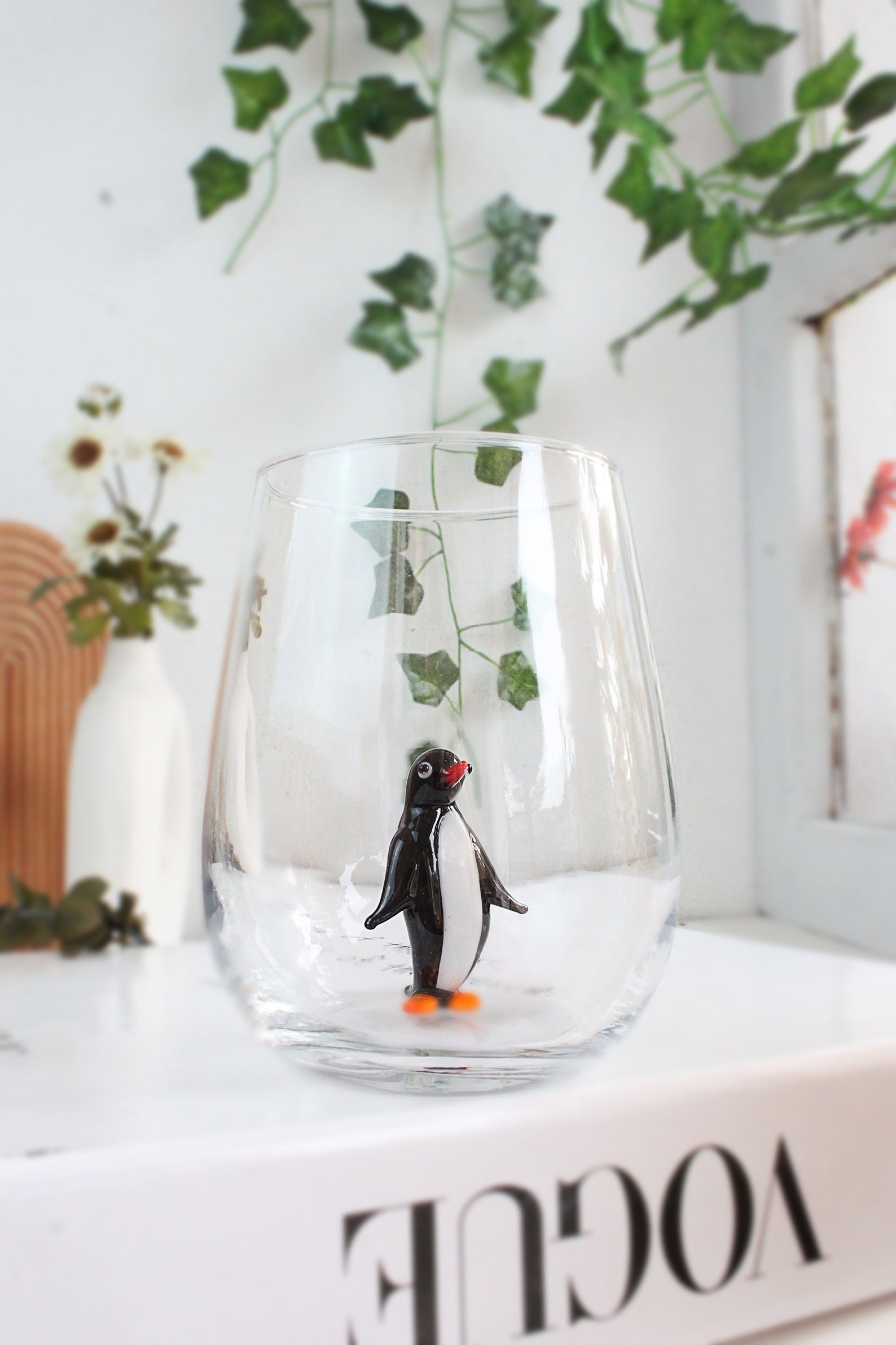 glass with a black penguin painted on the side