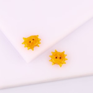 Op de afbeelding: Twee gele glazen zonne-oorbellen met zwarte kraaloogjes.