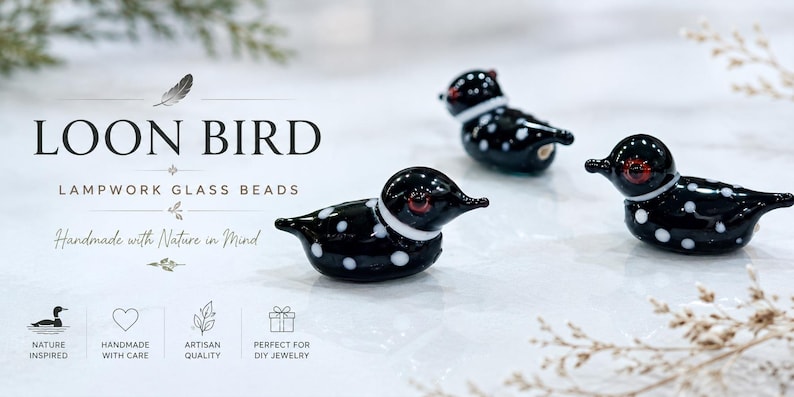Puede incluir: Tres cuentas de vidrio negro y blanco con forma de somorgujo, con lunares blancos y ojos rojos. El texto "LOON BIRD" y "LAMPWORK GLASS BEADS" se muestra encima de los p&aacute;jaros. Tambi&eacute;n es visible la frase "Handmade with Nature in Mind".