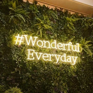 Texto de hashtag em luzes de néon, frase iluminada por néon LED e sinal de ditado, palavras iluminadas atraentes para parede de flores verdes com dimmer