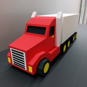 May include: A red toy truck with a white trailer. The truck has a black grill and yellow headlights. The trailer has black wheels with yellow hubs.