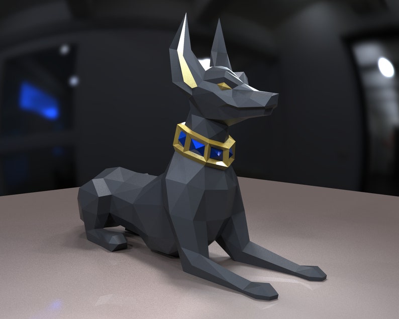 K&ouml;nnte beinhalten: Eine schwarze Anubis-Statue aus Origami mit einem goldenen Halsband und blauen Edelsteinen. Die Statue liegt mit dem Kopf zur Seite gedreht.