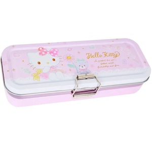 May include: A pink metal pencil case with a Hello Kitty design. The case features Hello Kitty and a bear with a flower. The text "Hello Kitty" and "A present for you filled with friendship and fun" is printed on the case.