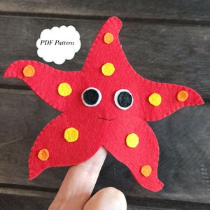 May include: Red felt finger puppet shaped like a starfish with yellow and orange polka dots, white eyes, and a black mouth.  The puppet is on a finger.