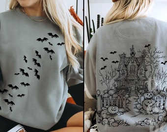 May include: A gray sweatshirt with a black graphic of a haunted house and bats on the back. The front of the sweatshirt has a black graphic of bats flying in a diagonal line.