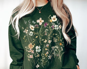 May include: A dark green sweatshirt with a floral print featuring a variety of flowers and butterflies in shades of pink, purple, yellow, and white.