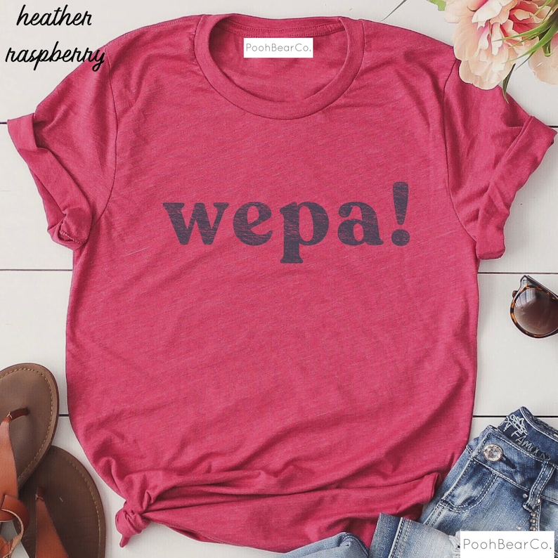 May include: A heather raspberry t-shirt with the word "wepa!" printed in black on the front. The shirt has a crew neck and short sleeves.