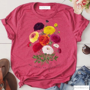 May include: A pink t-shirt with a floral design and the text "no rain, no flowers".