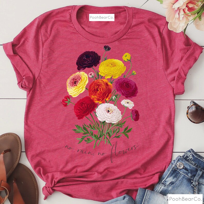 May include: A pink t-shirt with a floral design and the text "no rain, no flowers".