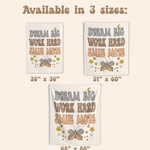 May include: A white tapestry with the text "DREAM BIG WORK HARD SMILE MORE" in a retro font. A butterfly with orange and brown wings is centered below the text. The tapestry is available in three sizes: 26 inches by 36 inches, 51 inches by 60 inches, and 68 inches by 80 inches.