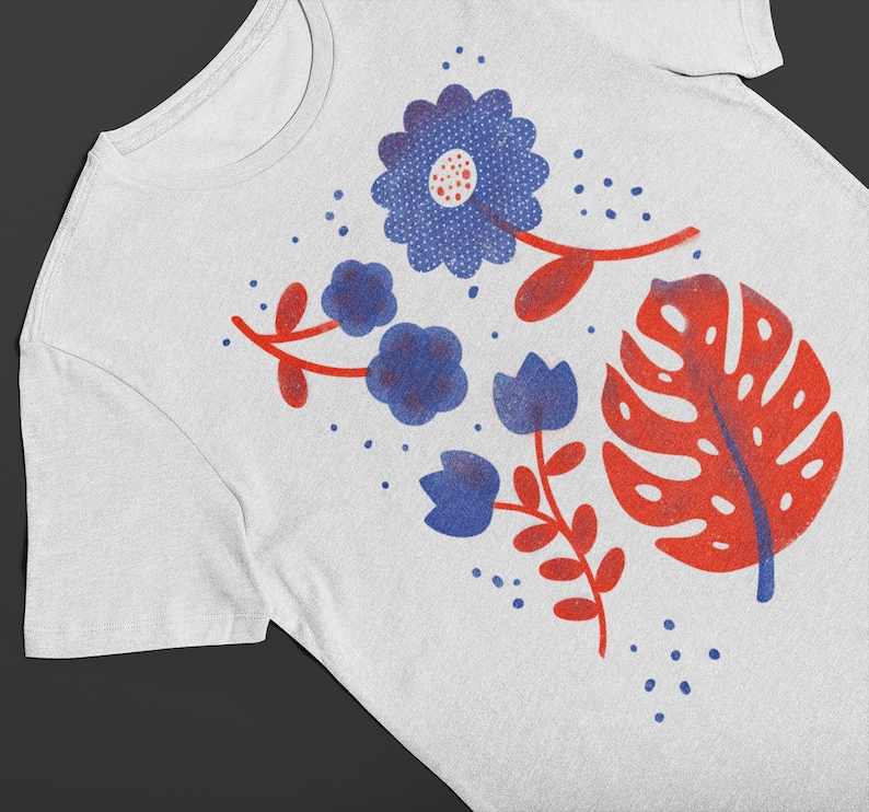 Puede incluir: Camiseta blanca con un dise&ntilde;o floral azul y rojo. El dise&ntilde;o incluye una flor azul grande con un centro rojo, flores azules m&aacute;s peque&ntilde;as y una hoja roja.