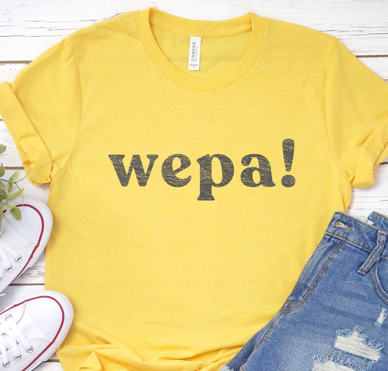 May include: Yellow t-shirt with the word "wepa!" printed in black.