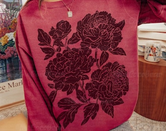 May include: Crimson-colored sweatshirt featuring a large floral design in a darker shade. The design includes several large peony blooms and leaves. The sweatshirt is a crew neck style and has long sleeves.