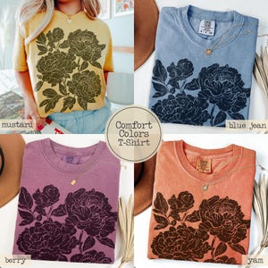 Puede incluir: Cuatro camisetas Comfort Colors en colores mostaza, azul jean, baya y &ntilde;ame. Cada camiseta de manga corta presenta un gr&aacute;fico floral oscuro y detallado de peon&iacute;as en la parte delantera. Las camisetas tienen cuello redondo y un corte relajado.