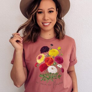 May include: A pink t-shirt with a floral bouquet graphic and the text "no rain, no flowers".