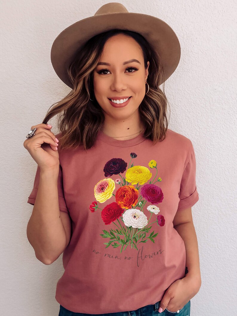 May include: A pink t-shirt with a floral bouquet graphic and the text "no rain, no flowers".