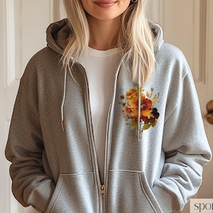 May include: A gray zip-up hoodie with a floral print on the left side of the chest. The print features a bouquet of orange, yellow, and brown flowers.