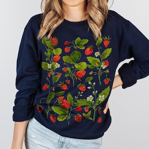 Puede incluir: Sudadera azul marino con un dise&ntilde;o bot&aacute;nico de fresas. El estampado incluye fresas rojas, hojas verdes y flores blancas. La parte superior de manga larga es de estilo casual y c&oacute;modo.