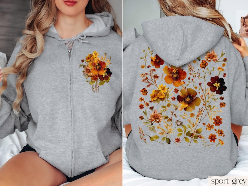 May include: A gray zippered hoodie with a floral print on the front and back. The flowers are in shades of orange, brown, and yellow. The hoodie is labeled "sport grey".