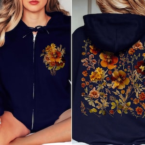May include: A navy blue hoodie with a floral print featuring orange, yellow, and brown flowers. The hoodie has a zipper closure and a hood.