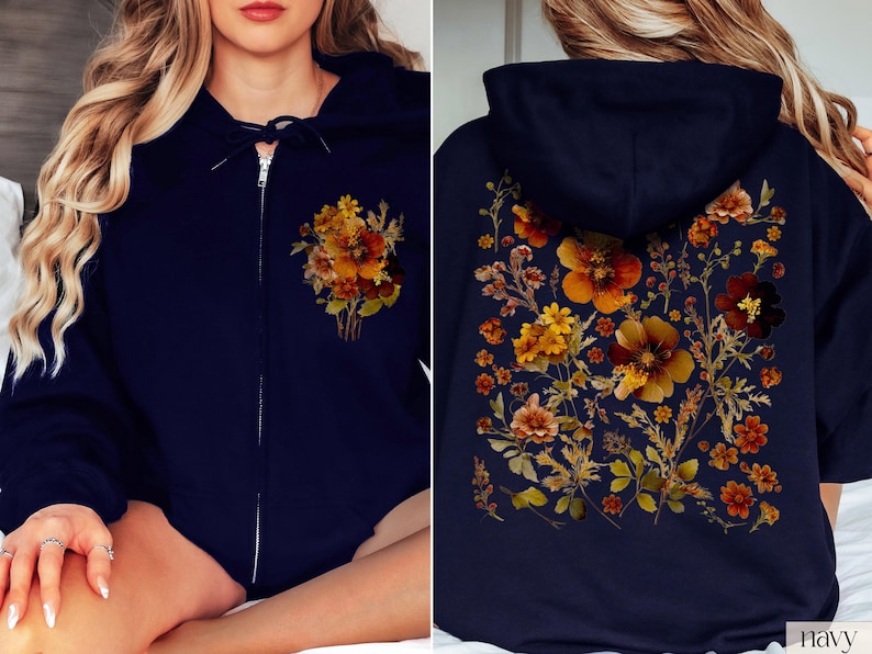 May include: A navy blue hoodie with a floral print featuring orange, yellow, and brown flowers. The hoodie has a zipper closure and a hood.