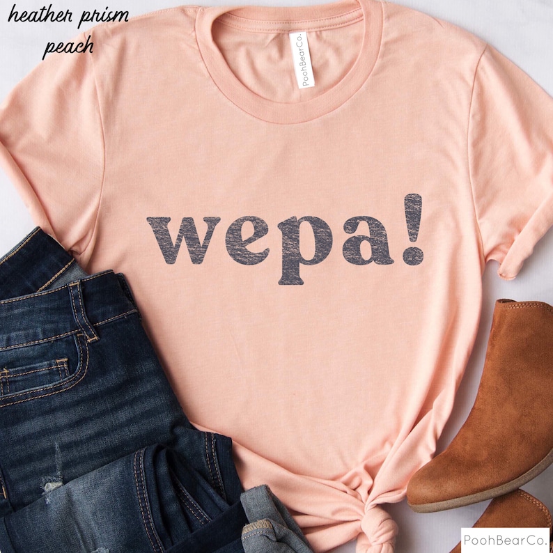 May include: A peach colored t-shirt with the word "wepa!" printed in black on the front.