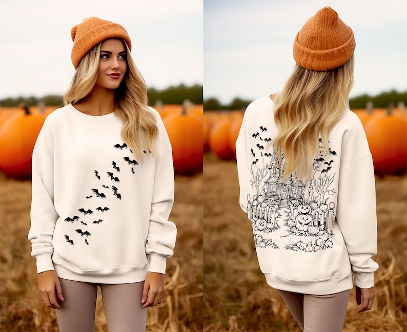 Op de afbeelding: Een wit sweatshirt met een zwart vleermuisontwerp aan de voorkant en een zwart spookhuisontwerp aan de achterkant. Het model draagt ​​een bruine beanie.