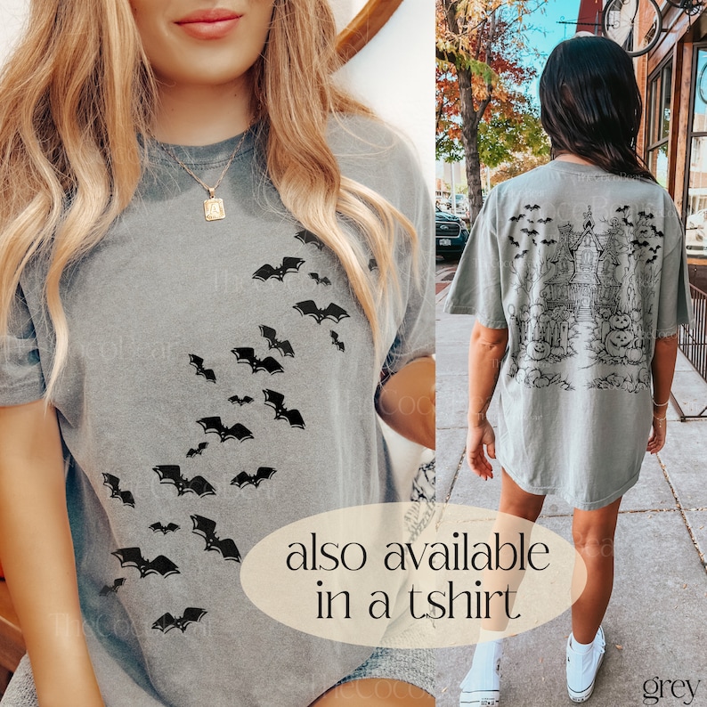 Op de afbeelding: Een grijs T-shirt met een zwart vleermuisontwerp. Het shirt is verkrijgbaar in een T-shirt stijl. De tekst "ook verkrijgbaar als T-shirt" is gedrukt op de onderkant van de afbeelding. Het woord "grijs" is gedrukt in de rechterbenedenhoek van de afbeelding.