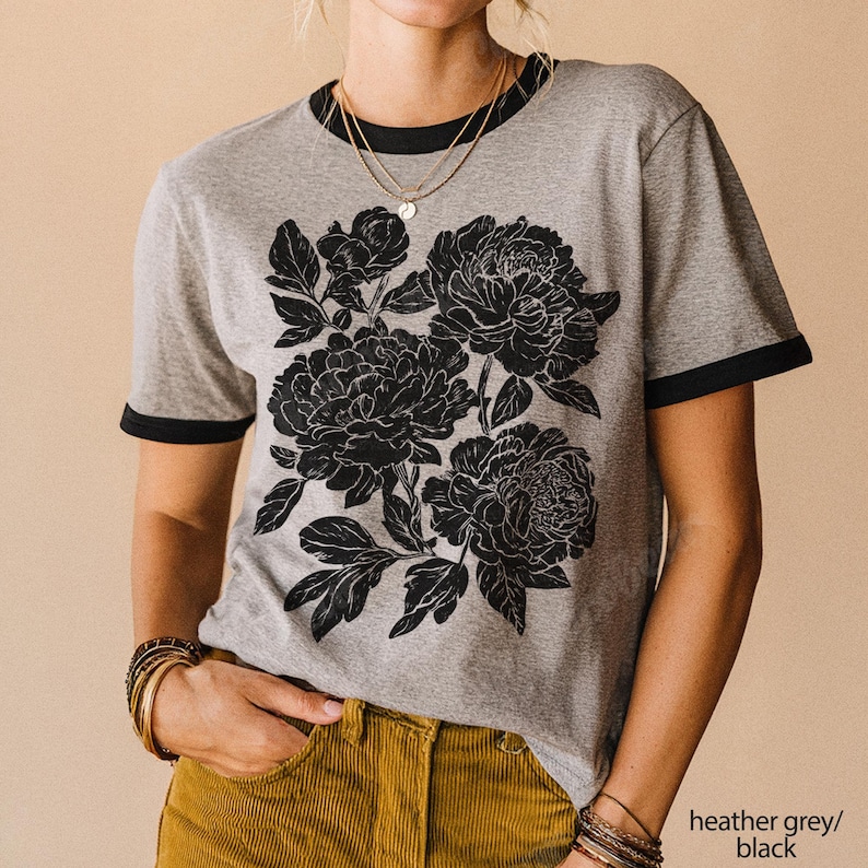 May include: Heather grey t-shirt with black trim and a large black floral design. The shirt has short sleeves and a crew neck. The text "heather grey/black" is in the bottom right corner.
