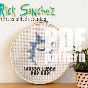 May include: A cross stitch pattern of Rick Sanchez from the animated series Rick and Morty. The pattern is in a wooden embroidery hoop and features Rick's face and the phrase "Wubba Lubba Dub Dub!" in black thread.