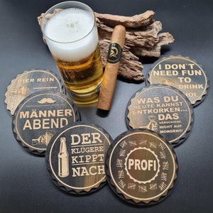 Può includere: Sei sottobicchieri in legno con diversi detti. I sottobicchieri sono neri con un motivo a venature di legno marrone. I detti sui sottobicchieri sono: "Bier Rein", "Männer Abend", "Der Kluggere Kippt Nach", "Was Du Heute Kannst Entkorken... Das Verschiebe Nicht Auf Morgen!!!", "I Don't Need Fun To Drink Yol", e "Profi".