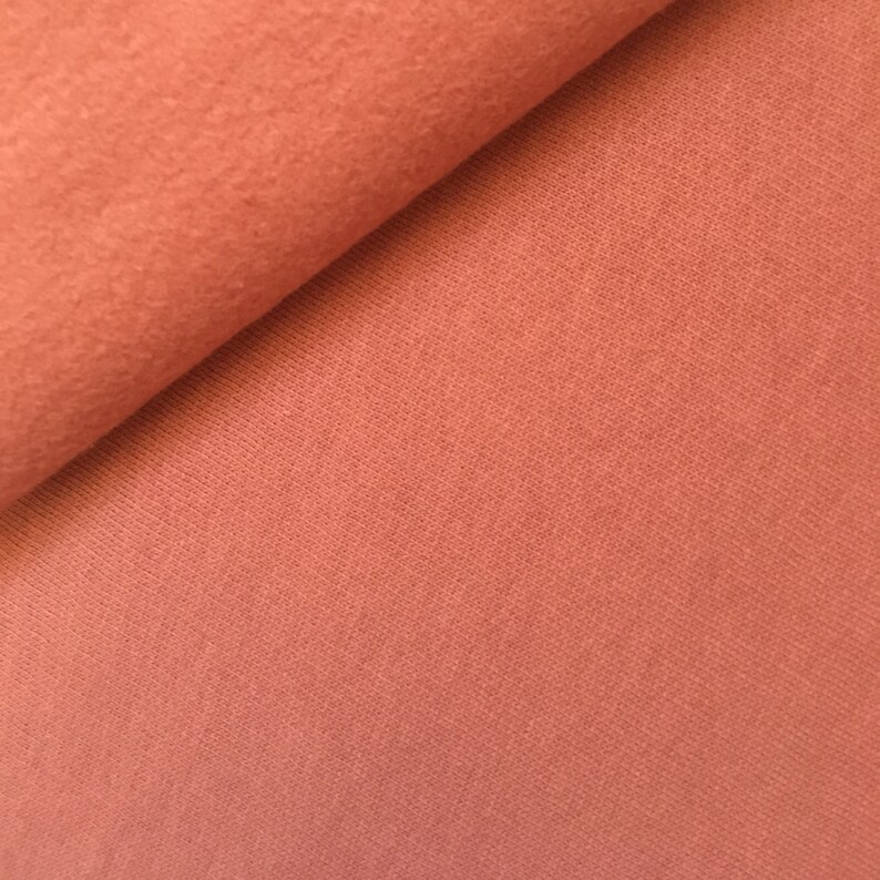 May include: Close-up of a soft, terracotta-colored fabric with a textured surface.
