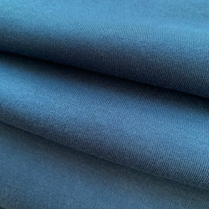 Könnte beinhalten: Nahaufnahme eines gefalteten Stücks dunkelblauen Stoffes mit einer strukturierten Oberfläche. Der Stoff fühlt sich weich und angenehm an.