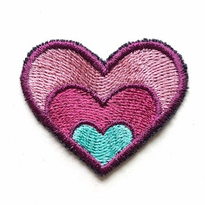 Può includere: Toppa a forma di cuore ricamata con un design a strati. Il cuore esterno è rosa chiaro, il cuore centrale è magenta e il cuore interno è turchese. La toppa ha un bordo viola scuro e si trova su uno sfondo bianco.