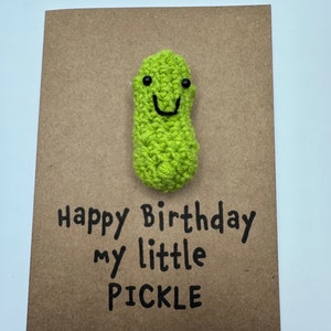 May include: A brown card with the text "Happy Birthday my little PICKLE" and a green crocheted pickle with a smiling face.