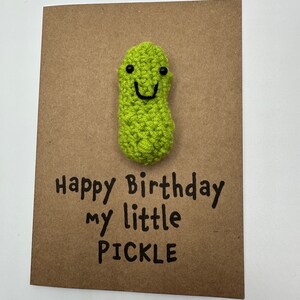 May include: A brown card with a green crocheted pickle with a smiling face. The card says "Happy Birthday my little PICKLE".