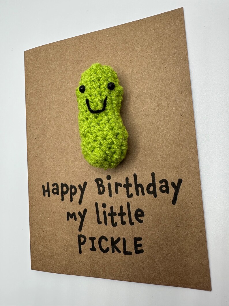 May include: A brown card with a green crocheted pickle with a smiling face. The card says "Happy Birthday my little PICKLE".