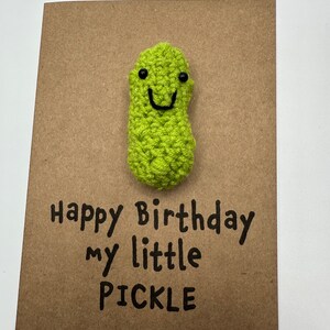 May include: A brown card with a green crocheted pickle with a smiling face and the text "Happy Birthday my little PICKLE"