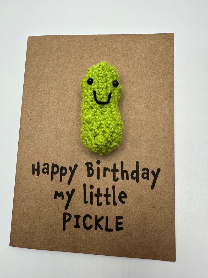 May include: A brown card with a green crocheted pickle with a smiling face and the text "Happy Birthday my little PICKLE"