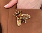 Golden brown fly brooch.The insect brooch is a perennial trend. A yellow brooch fly will decorate a black or brown dress,as well as any coat