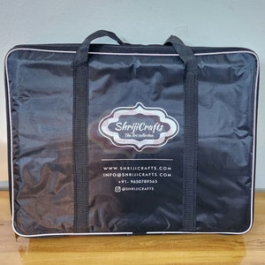 May include: A black rectangular carrying case with two top handles and a zipper closure. The front features a white logo with the text ShrijiCrafts The Art collection, along with website, email, phone number, and social media handle information.