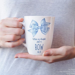 May include: White ceramic mug with a blue watercolor bow and the text "When in doubt put a BOW on it".