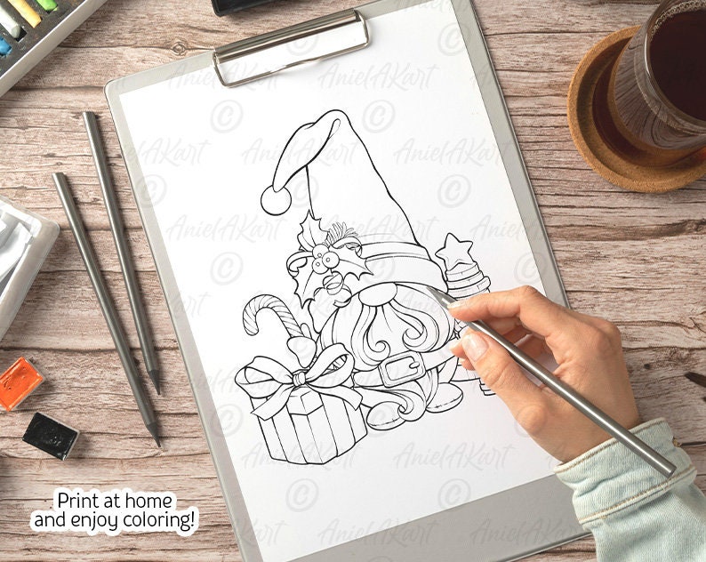 Op de afbeelding: Een zwart-witte printbare kleurplaat met een kerstgnome met een grote hoed, een cadeau en een snoepstok. De tekst "Print thuis en geniet van het kleuren!" staat onderaan de pagina.