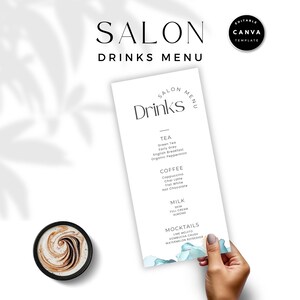 Op de afbeelding: Een witte drankkaart met de tekst "SALON DRINKS MENU" en een lijst met drankjes. Het menu wordt door een hand vastgehouden en bevat thee, koffie, melk en mocktails. Een kopje koffie met een wervelontwerp staat in de linker benedenhoek.