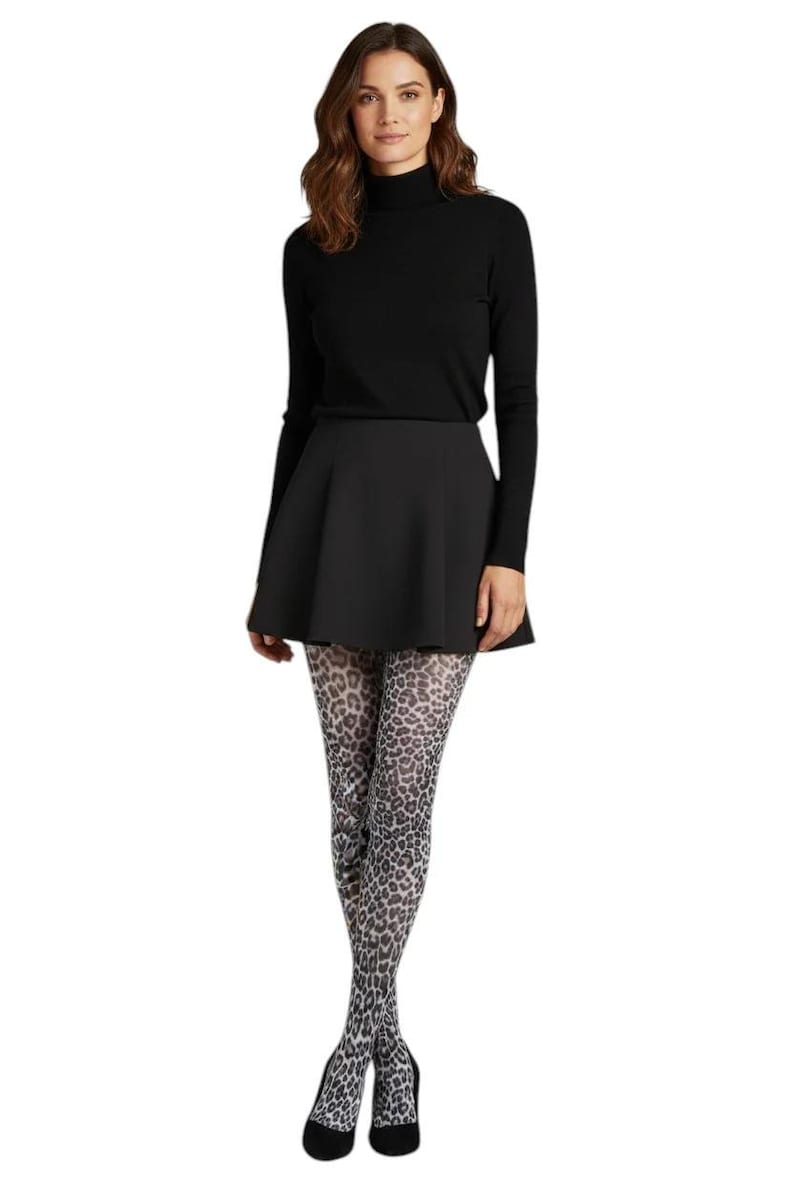 A woman standing, wearing a black turtleneck top, black mini skirt, black high heels, and white and grey monochrome leopard print patterned tights.