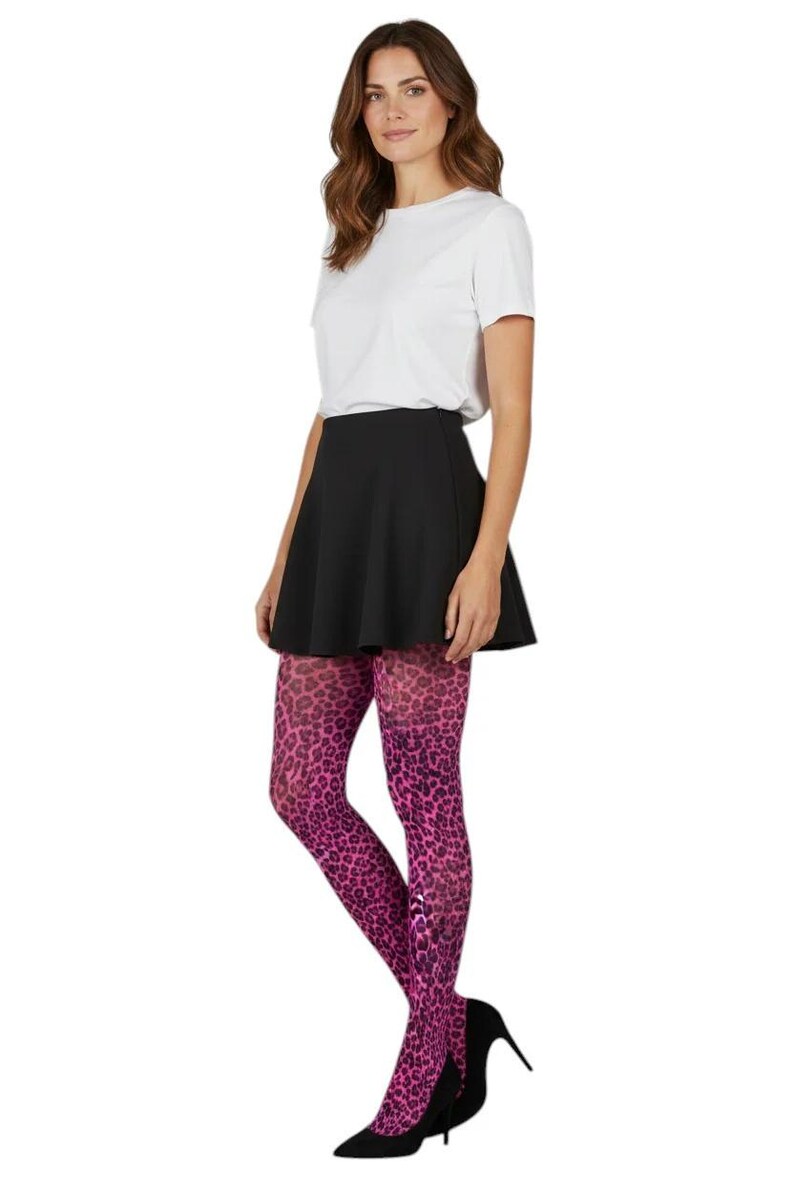 A woman standing with hands in pockets, wearing a white long-sleeved top, black mini skirt, black ankle boots, and dark neon pink leopard print patterned tights.